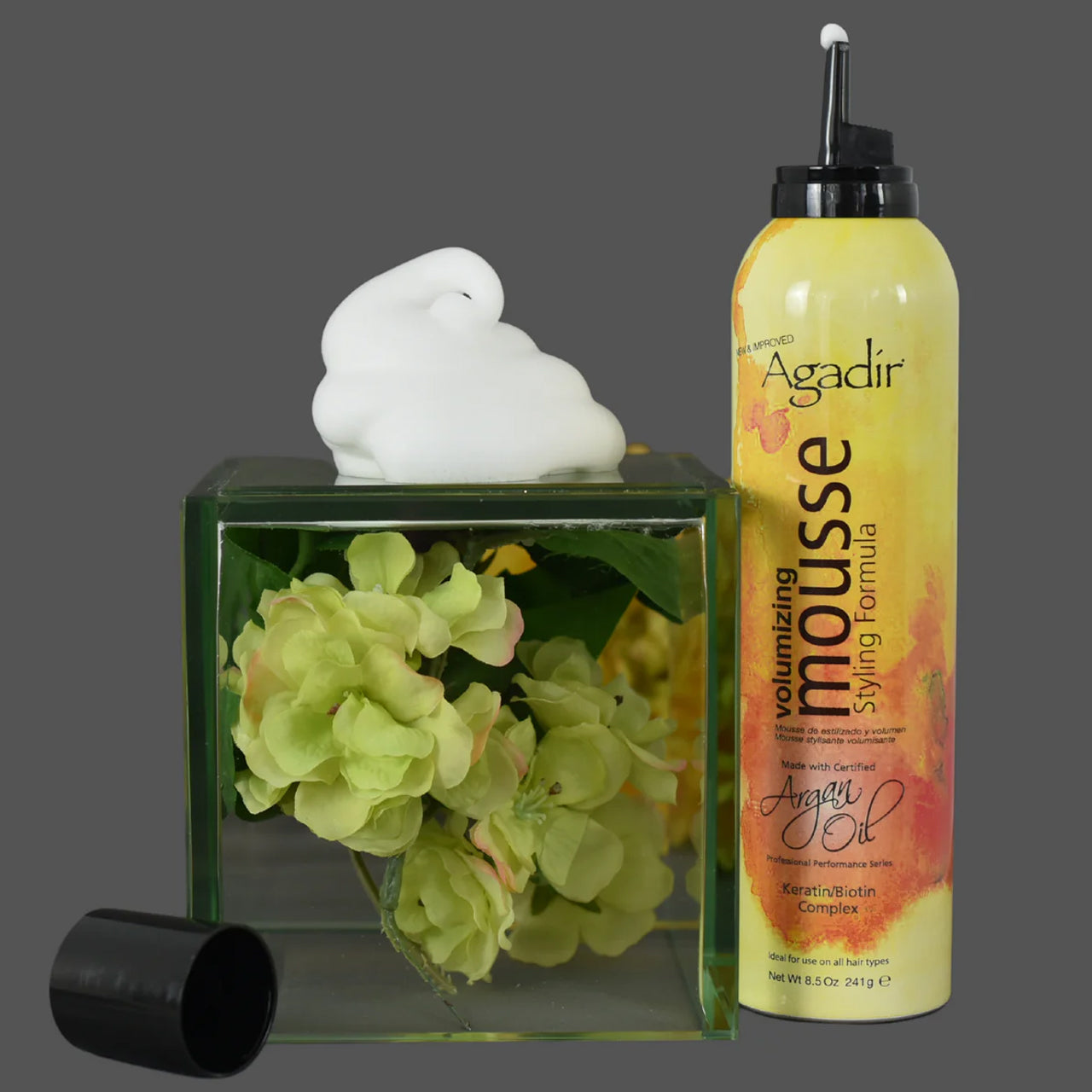 Agadir Argan Oil Volumising Styling Mousse can next to argan nuts and oil, highlighting natural ingredients.