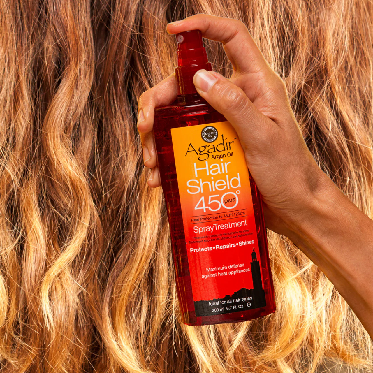 Hairstylist applying Agadir Hair Shield 450 Plus Spray to a client's hair before styling.