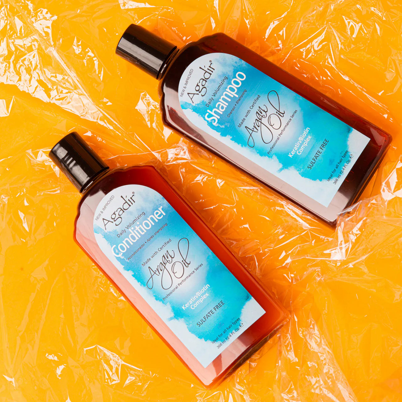 Agadir Argan Oil Daily Volumising Shampoo 1L bottle next to argan nuts and oil, highlighting natural ingredients.